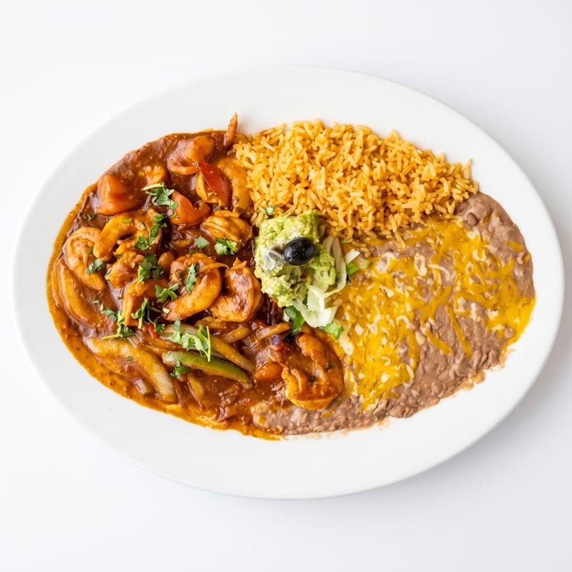 Shrimp fajitas with rice, refried beans, guacamole, and a black olive on a white plate.